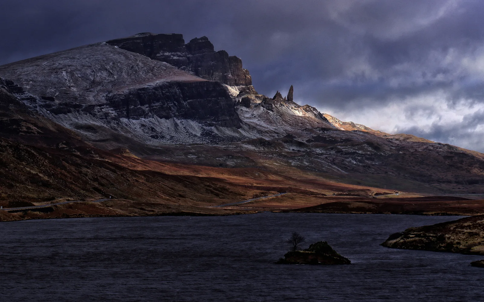 Old Man of Storr oberhalb von Loch Fada unter dunklen Wolken auf der Isle of Skye